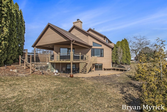 rear view of property with a lawn, stairs, a wooden deck, a chimney, and a patio area