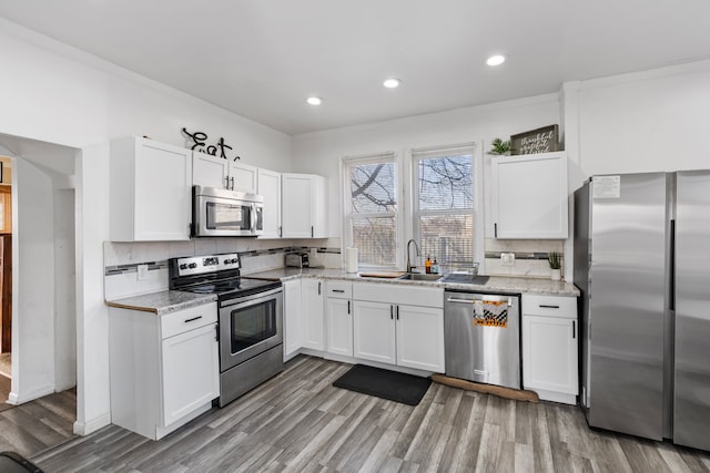 kitchen featuring backsplash, white cabinets, stainless steel appliances, and a sink