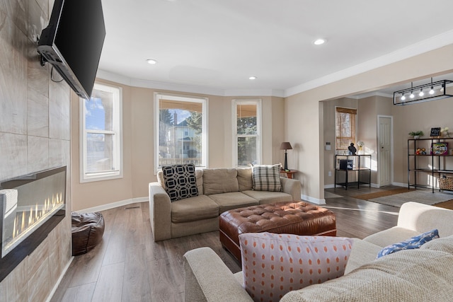 living room featuring wood finished floors, recessed lighting, a fireplace, crown molding, and baseboards