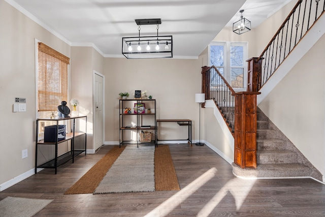 entryway featuring a notable chandelier, wood finished floors, crown molding, baseboards, and stairs