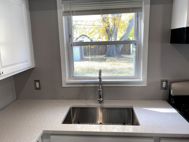 kitchen featuring a sink, light stone countertops, and white cabinets