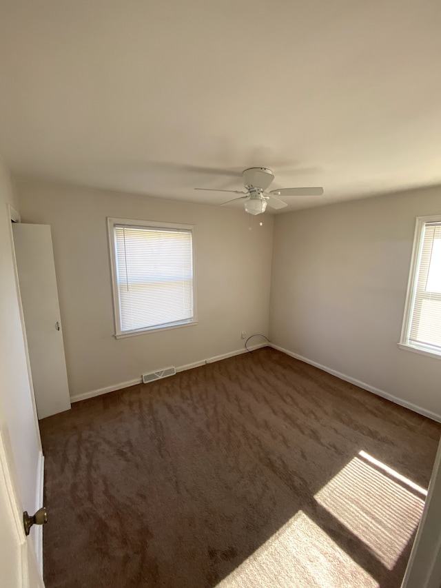 empty room featuring visible vents, carpet flooring, and a ceiling fan