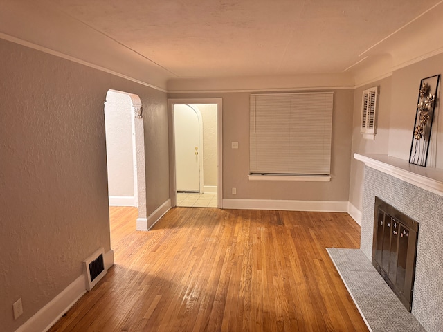 unfurnished living room featuring hardwood / wood-style floors, baseboards, visible vents, and a tile fireplace