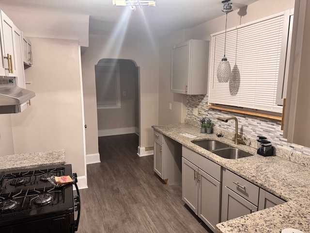 kitchen featuring light stone countertops, black gas range, range hood, dark wood-style floors, and a sink