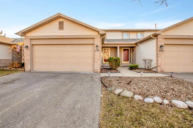 view of front of home with aphalt driveway, an attached garage, and brick siding