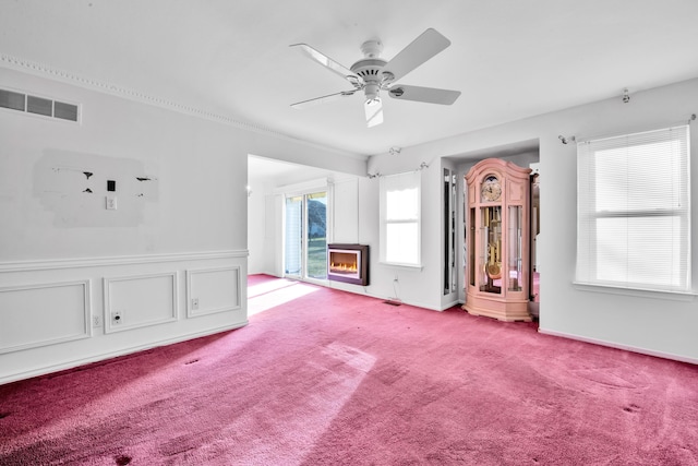 interior space with visible vents, ceiling fan, a wainscoted wall, light colored carpet, and a decorative wall