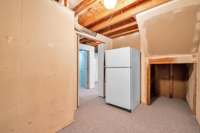 unfinished basement with freestanding refrigerator