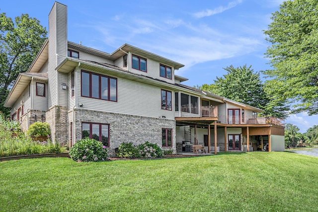 rear view of property with brick siding, a lawn, french doors, a chimney, and a patio