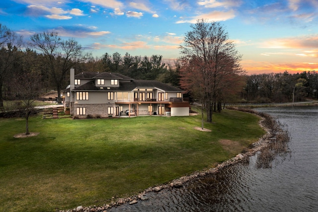 rear view of property with a lawn, a chimney, and a water view