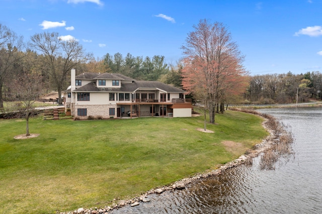 back of house with a lawn, a chimney, gravel driveway, and a deck with water view