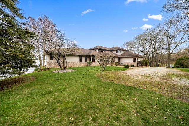 view of front of home featuring stone siding and a front lawn