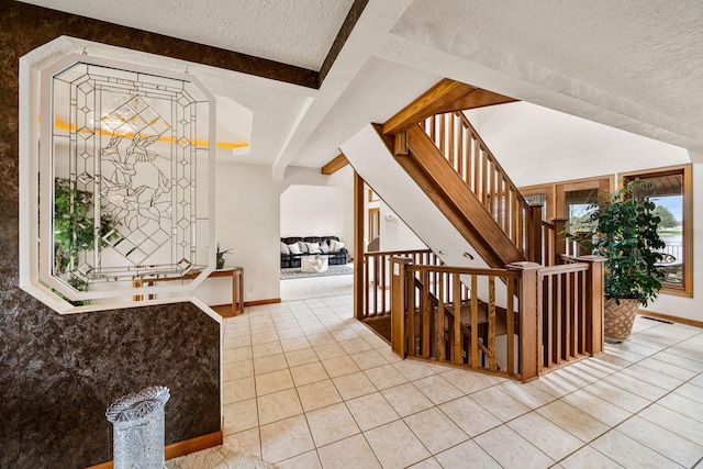 foyer entrance featuring stairway, light tile patterned flooring, baseboards, and a textured ceiling