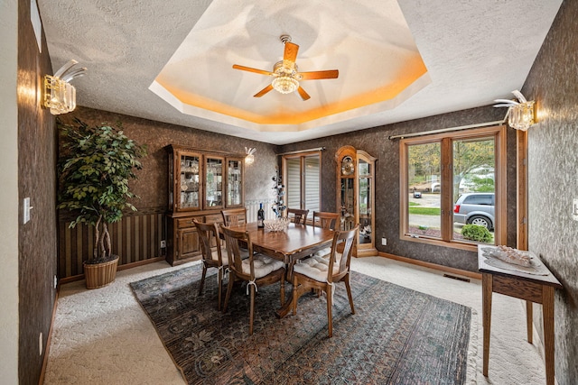 carpeted dining room featuring ceiling fan, a tray ceiling, and a textured ceiling