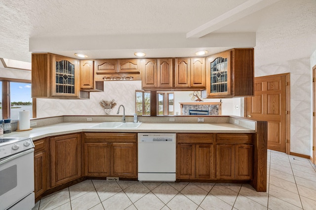 kitchen with a sink, white appliances, brown cabinetry, and light countertops