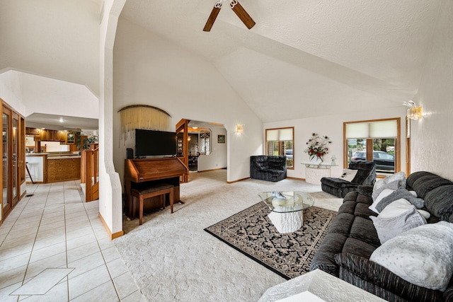 living room featuring high vaulted ceiling, a ceiling fan, arched walkways, light tile patterned flooring, and light colored carpet