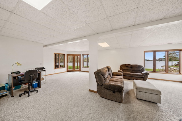 carpeted living area with a drop ceiling and baseboards