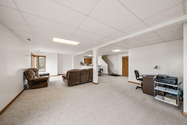 carpeted living room featuring a drop ceiling, stairway, and baseboards