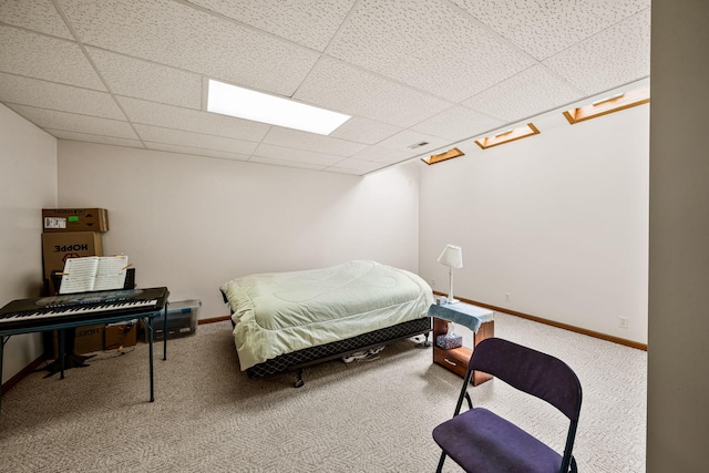 carpeted bedroom with baseboards and a drop ceiling