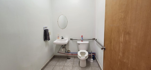 half bathroom with tile patterned floors, toilet, baseboards, and a sink