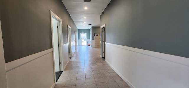 hallway with light tile patterned flooring and baseboards