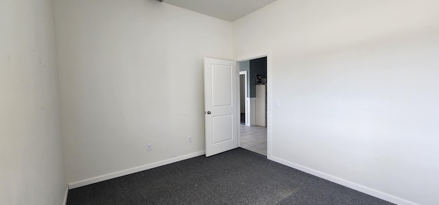 empty room with baseboards and dark colored carpet