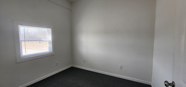 unfurnished room with dark carpet and baseboards