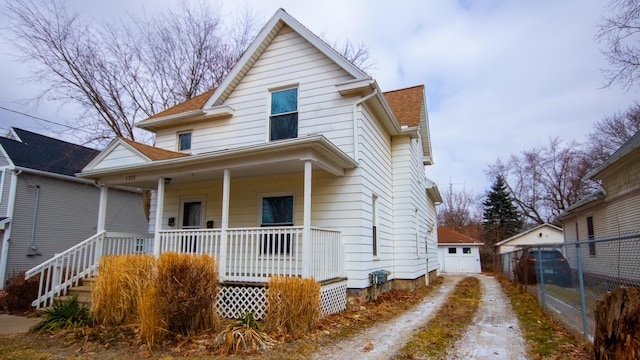 view of front of property with a porch, dirt driveway, and a shingled roof