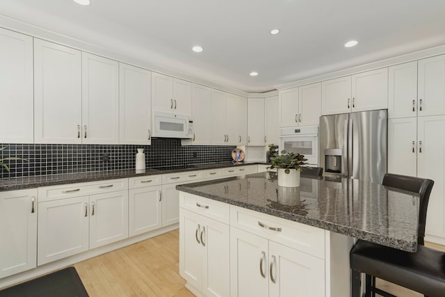 6264 Wildwood Ln, West Bloomfield, MI 48324 - kitchen featuring white appliances, a breakfast bar area, light wood finished floors, white cabinets, and recessed lighting