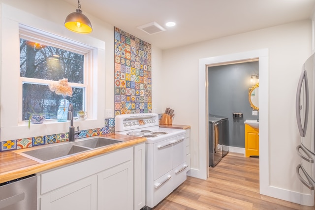 kitchen featuring appliances with stainless steel finishes, light wood-style floors, independent washer and dryer, white cabinetry, and a sink