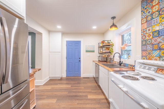 kitchen featuring light wood-type flooring, recessed lighting, white cabinets, stainless steel appliances, and a sink