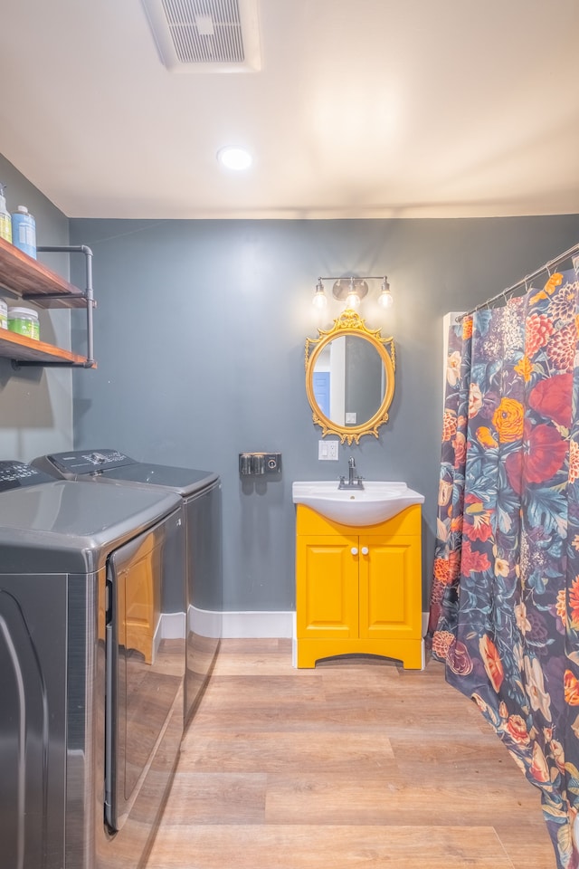 full bath featuring vanity, wood finished floors, visible vents, baseboards, and separate washer and dryer