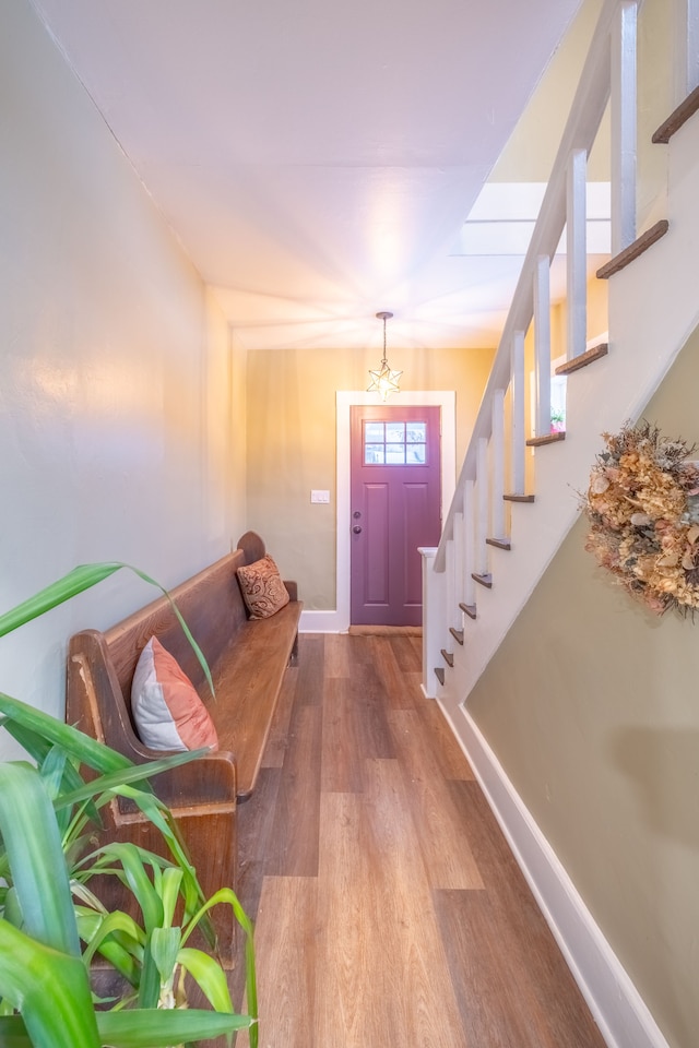 foyer entrance with a notable chandelier, stairs, baseboards, and wood finished floors