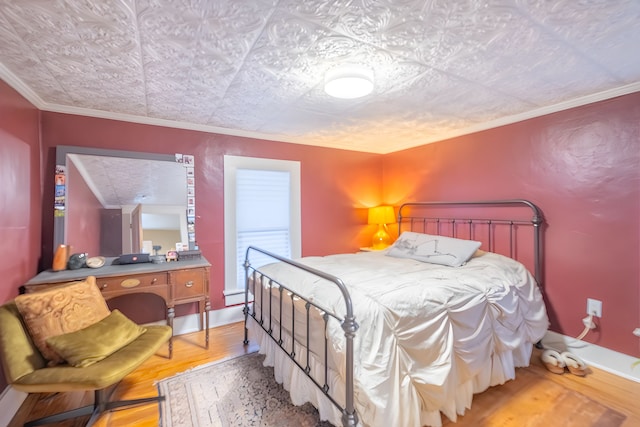 bedroom with crown molding, baseboards, light wood-type flooring, and an ornate ceiling