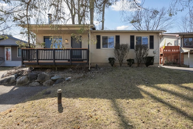 ranch-style house featuring a deck and a front lawn