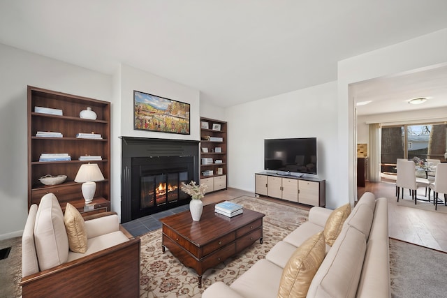 living area with a fireplace with flush hearth and wood finished floors