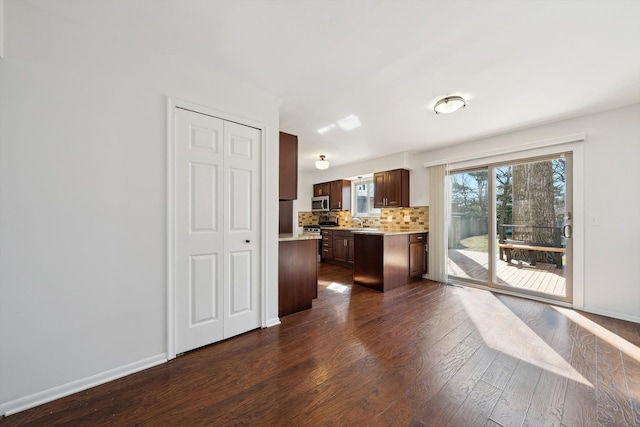 kitchen with dark wood-type flooring, backsplash, dark brown cabinetry, light countertops, and baseboards