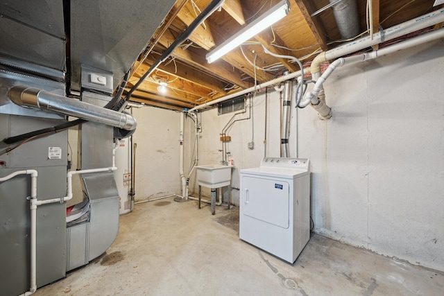 unfinished below grade area with heating unit, visible vents, washer / clothes dryer, a sink, and gas water heater