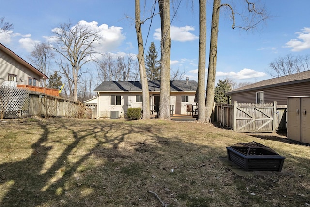 back of house with a fire pit, fence, and a lawn