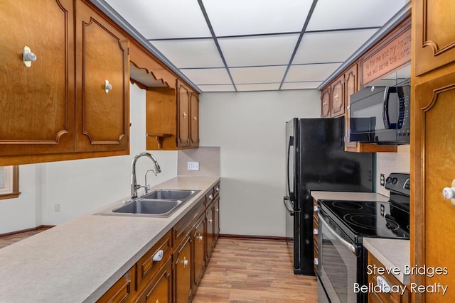 kitchen featuring brown cabinetry, stainless steel electric range oven, black microwave, and a sink