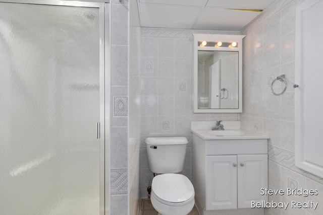 full bath with vanity, tile walls, toilet, and a shower stall