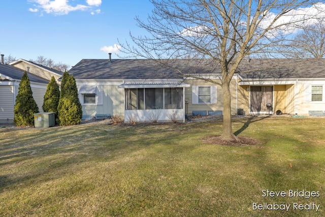 rear view of house with a yard, a shingled roof, and a sunroom