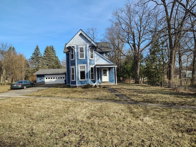 victorian-style house featuring concrete driveway, an attached garage, and a front yard
