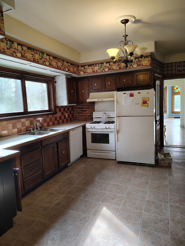kitchen featuring under cabinet range hood, an inviting chandelier, a sink, white appliances, and dark brown cabinetry