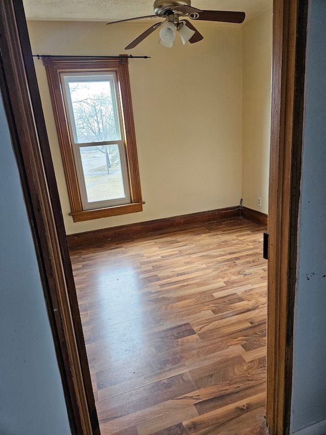 unfurnished room featuring baseboards, wood finished floors, and a ceiling fan