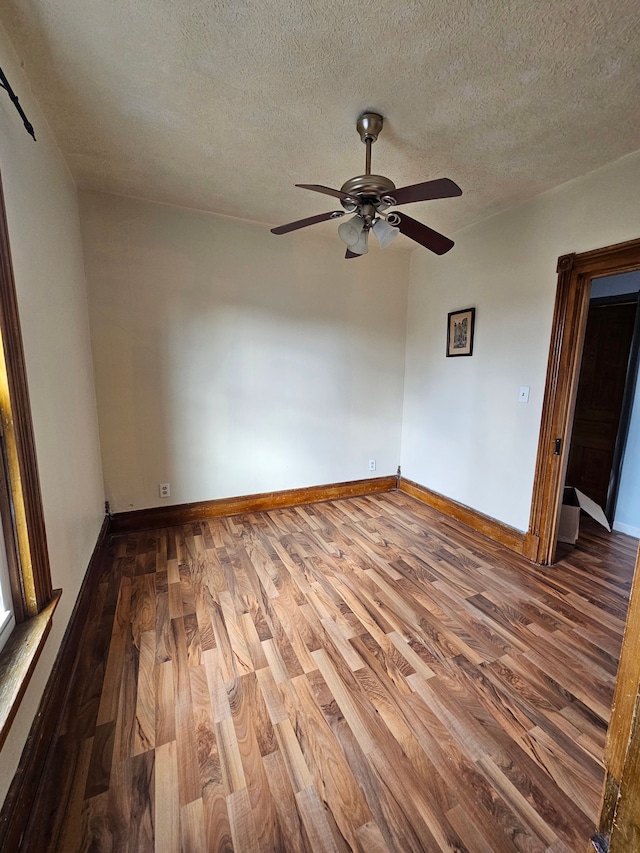 unfurnished room featuring a textured ceiling, wood finished floors, a ceiling fan, and baseboards