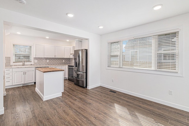 kitchen with visible vents, dark wood finished floors, butcher block countertops, white cabinets, and stainless steel fridge