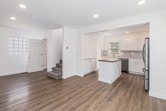 kitchen with plenty of natural light, white cabinets, butcher block counters, and stainless steel appliances