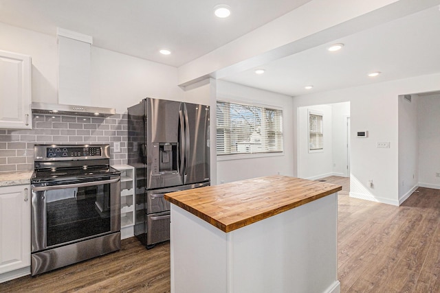 kitchen with butcher block countertops, stainless steel appliances, wall chimney exhaust hood, and dark wood-style flooring