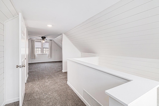 corridor with visible vents, baseboards, lofted ceiling, carpet floors, and an upstairs landing