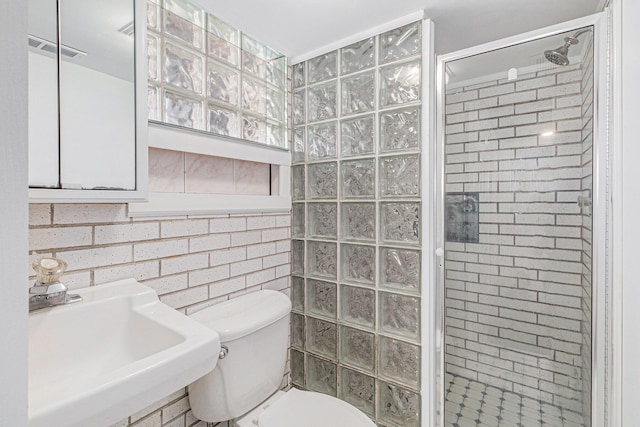 bathroom with visible vents, a shower stall, brick wall, toilet, and a sink